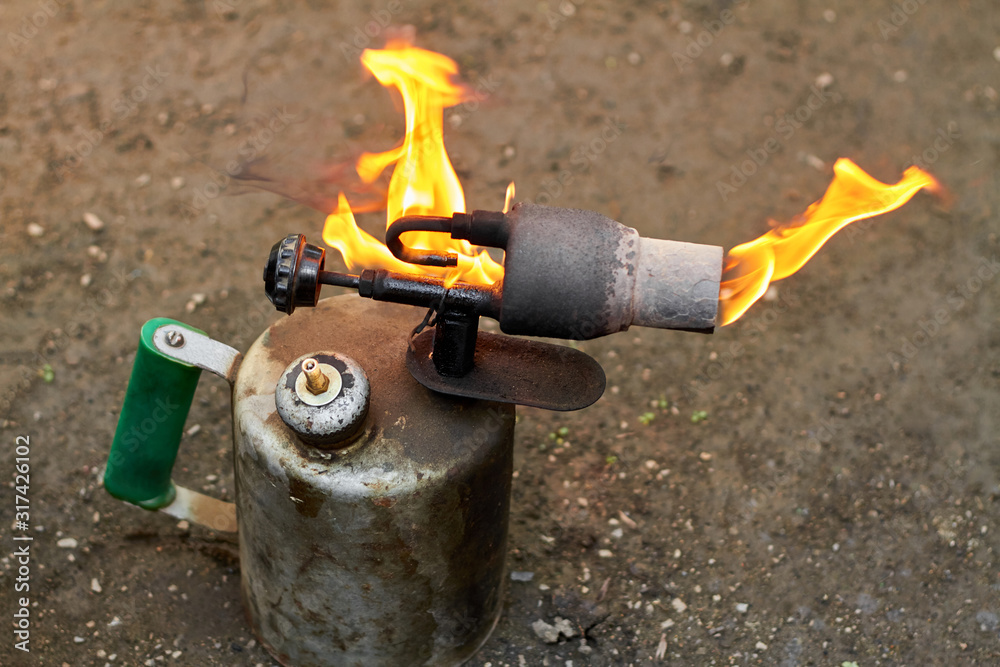 Old rusty blowtorch with fire.