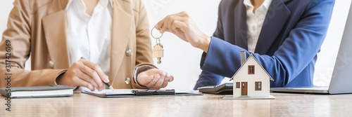 Real estate agent holding a key and asking costumer for contract to buy, get insurance or loan real estate or property. photo