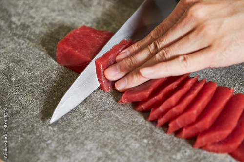 Foto Slicing tuna saku block with sashimi knife
