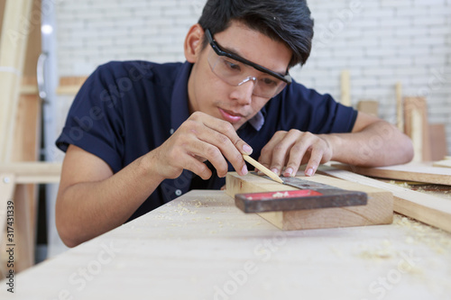Young asian carpenter measuring on wooden job with try square - Handyman and diy concept