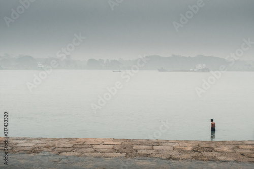 A man standing up in river at foggy morning 