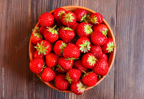red fresh strawberries in a plate on a wooden background