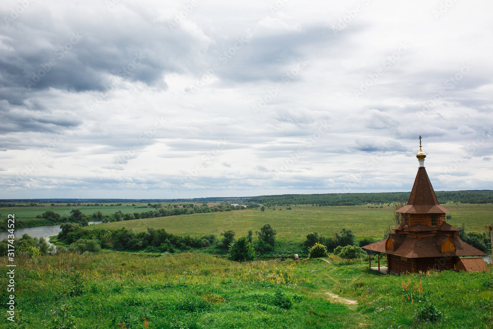 Authentic Russian wooden Church building on a high hill with panoramic views. Christian font on a high hill