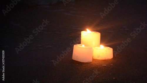 Three small candles on sandy beach near sea ocean waves burning photo