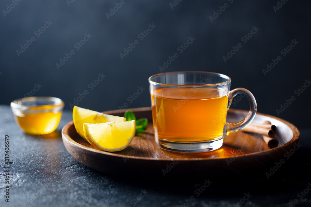 Tea cup with honey and lemon on wooden tray. Grey background. Copy space. Tea cup with honey and lemon on wooden tray. Grey background. Copy space.