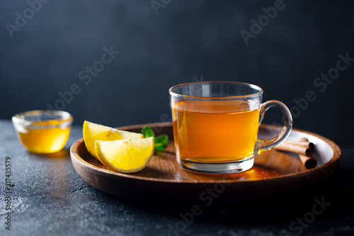 Tea cup with honey and lemon on wooden tray. Grey background. Copy space.
