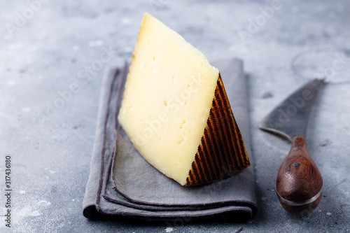 Hard cheese, Manchego with nuts on grey stone background. Close up. photo