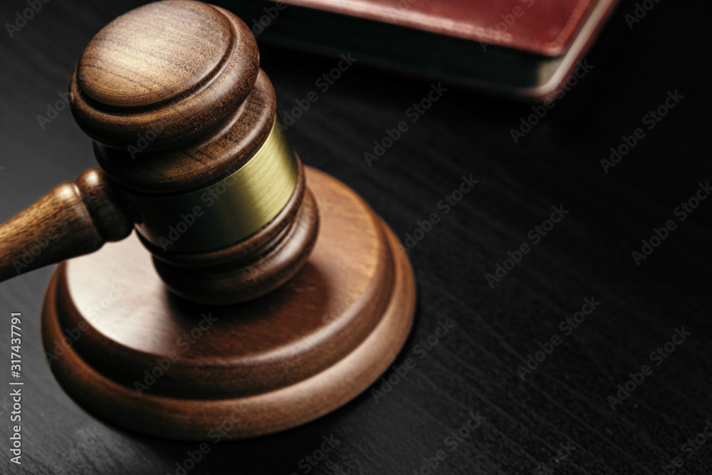 Judge's gavel on wooden table in dark