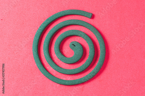 A green mosquito coil on a red background, top view photo