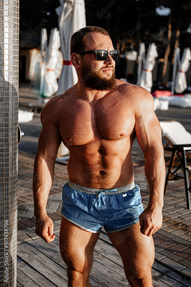 Obraz premium Muscular man bodybuilder tanning in a beach club