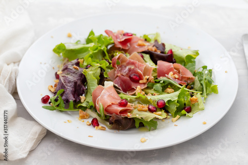 salad prosciutto with pomegranate on white plate