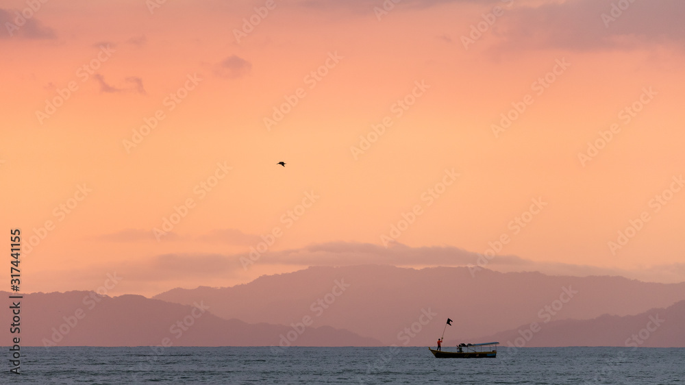 Sunset on the beaches of the Pacific Ocean in Costa Rica overlooking the Nicoya Peninsula, birds and fishermen.