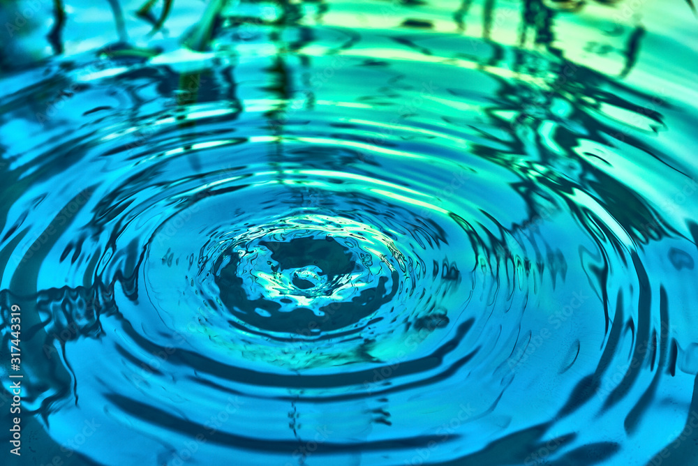 Raindrops fall on the surface of the water. The circles from the raindrops on the water surface. Abstract color background of circles on the water and falling drops. Raindrops fall on the surface of the water. The circles from the raindrops on the water surface. Abstract color background of circles on the water and falling drops.