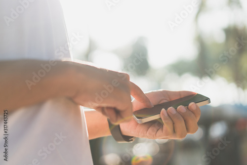 Male hands using his smart phone in sunlight