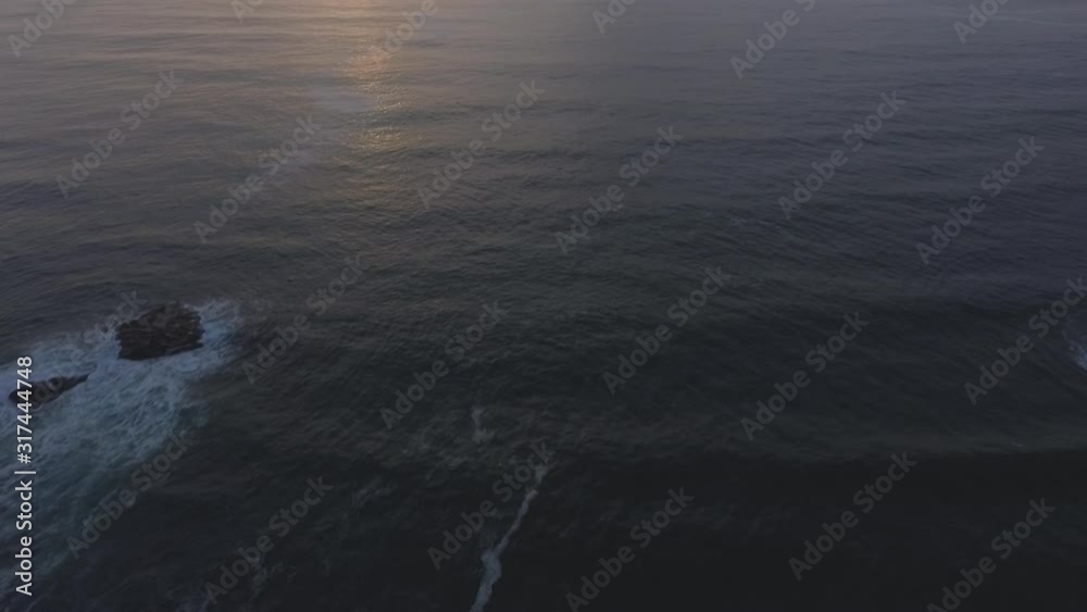 flyover view of the ocean from the waves break towards the horizon with sunset flyover view of the ocean from the waves break towards the horizon with sunset