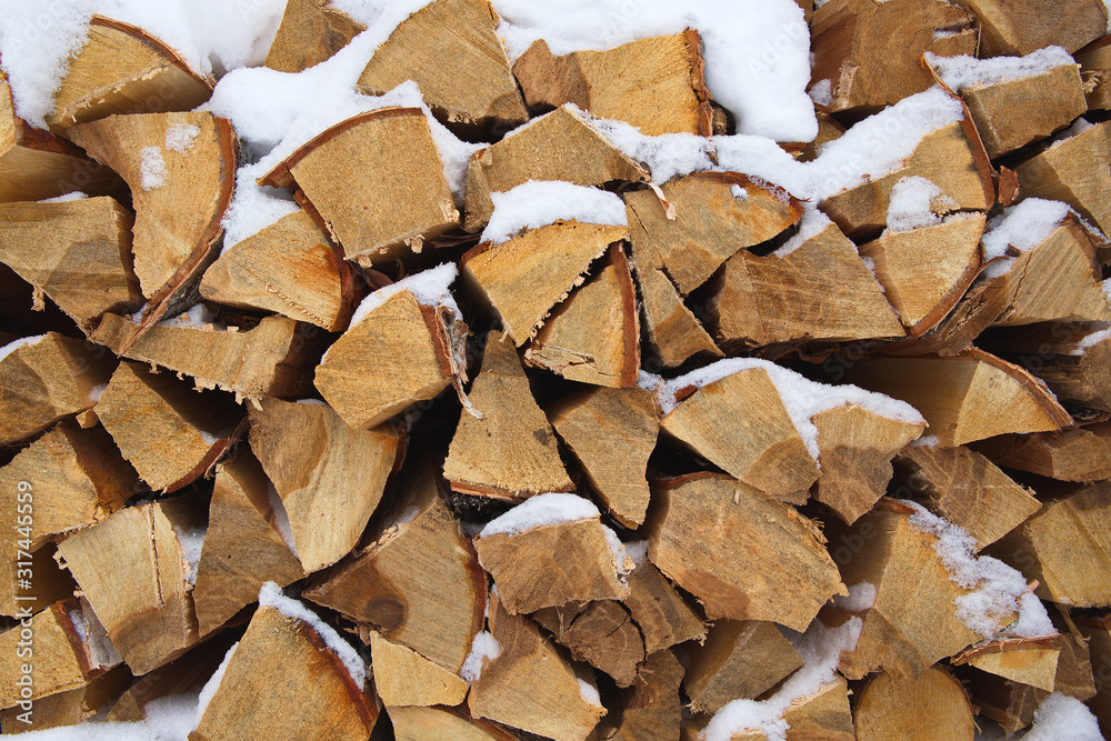 Chopped firewood in a woodpile. Snow lies on chopped wood. Background, wood fuel. Chopped firewood in a woodpile. Snow lies on chopped wood. Background, wood fuel.