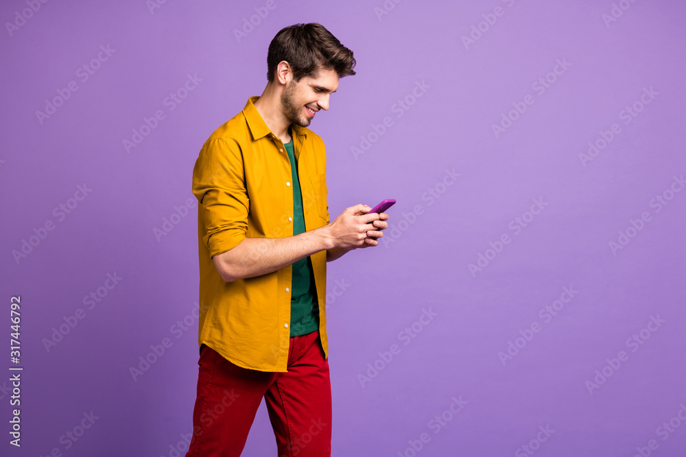 Photo of cheerful positive interested man chatting with his friends by using smartphone in pants red isolated pastel violet color background Photo of cheerful positive interested man chatting with his friends by using smartphone in pants red isolated pastel violet color background
