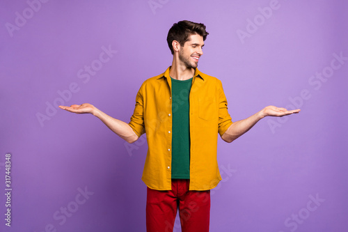 Photo of cheerful white man holding two objects empty space with hands smiling toothily isolated violet color pastel background