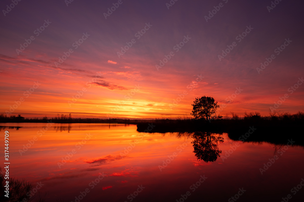 Spectacular sunrise at National park de groote peel in Limburg and North-Brabant in the Netherlands. Beautiful red and purple colors from sunset with reflection in the lake. Landscape the Netherlands Spectacular sunrise at National park de groote peel in Limburg and North-Brabant in the Netherlands. Beautiful red and purple colors from sunset with reflection in the lake. Landscape the Netherlands