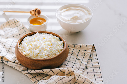 Healthy breakfast of cottage cheese with sour cream and honey on a marble table