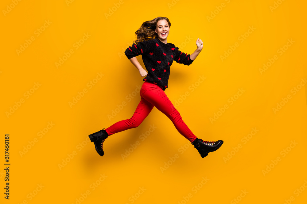 Full length profile photo of pretty lady jumping up high speed rushing low prices shopping wear hearts pattern sweater red trousers boots isolated yellow color background