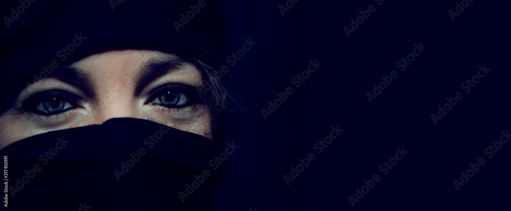 Closeup of the eyes of a caucasian woman with the face covered by a black wrap. Warrior. Feminist fight. Copy space. Closeup of the eyes of a caucasian woman with the face covered by a black wrap. Warrior. Feminist fight. Copy space.