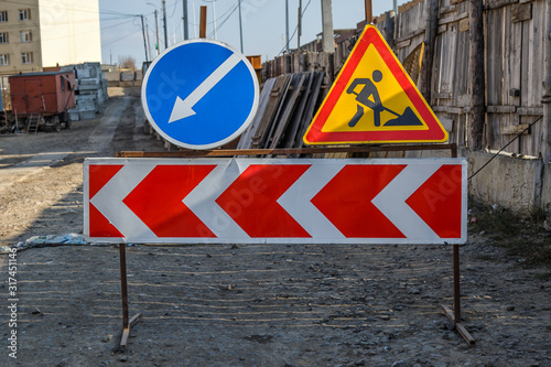 Work in progress. Roadworks, road signs. Men at work. Some signs signage for work in progress on urban street. Barriers and road signs. Silhouette of a worker at work. Right arrow.