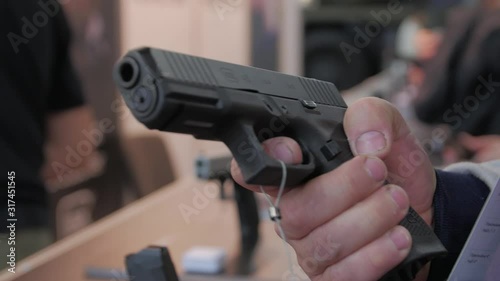 Man holding a gun buys chooses pistol in a military weapon store hands closeup
