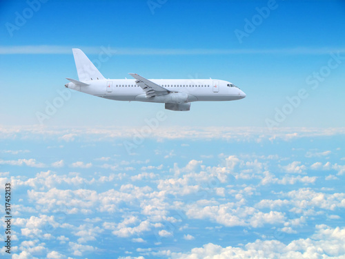 large white passenger plane flies high above the clouds