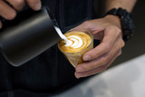 Barista making coffee with latte art, Created by pouring steamed milk into a shot of espresso and resulting in a pattern or design on the surface of the latte.