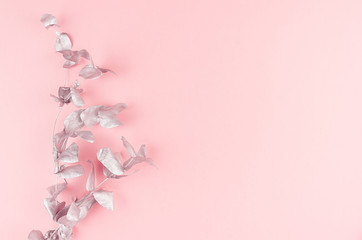 Elegant silver eucalyptus leaves as festive decorative border on soft light pastel pink background, copy space, top, view.