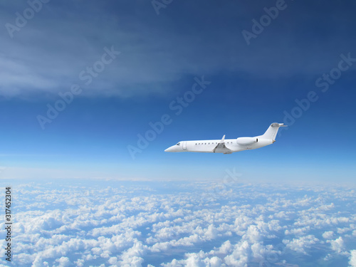 White private jet business jet flies against backdrop of beautiful white clouds on blue sky © sommersby