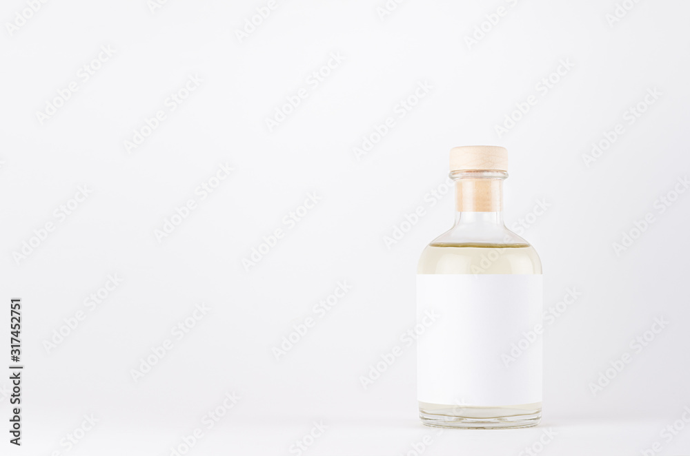 Transparent glass bottle for cosmetic, perfume, alcohol drink with  white label, cork, yellow liquid on white background, mock up for design.