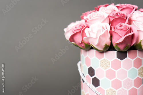 Flowers in bloom: A bouquet of pink and white roses in a round box on a gray background.