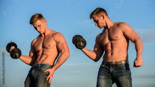 Adding weight on bar. Try to lift more than last time. Muscular twins. Men brothers muscular guys sky background. Strong muscular athlete bodybuilder. Attractive twins. Sexy torso attractive body photo