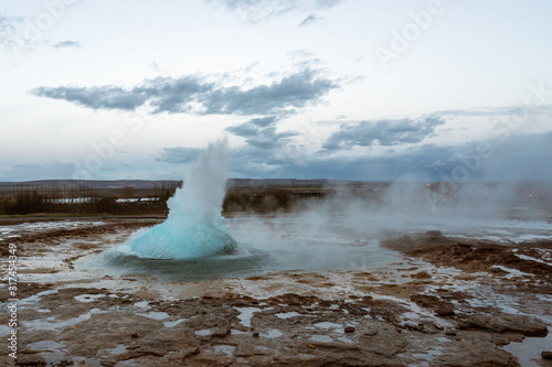The famous geysir/Strokur with explosion, in Haukadalur valley near Reykjavik in Iceland during blue hour with no people around. Traveling and explorer concept.