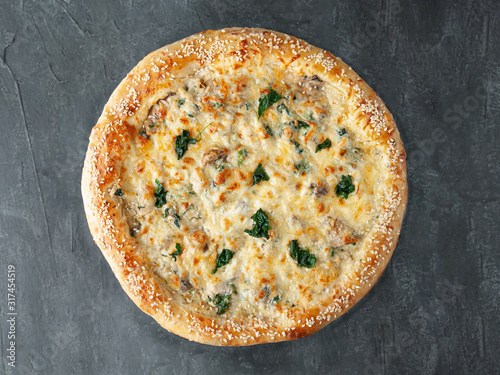 Italian pizza. With chicken, spinach and mushrooms. In creamy sauce, with mozzarella and sulguni cheeses. Wide side. View from above. On a gray concrete background. Isolated.