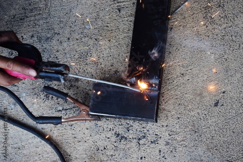 The mechanic is welding the black steel, creating a white spark.
