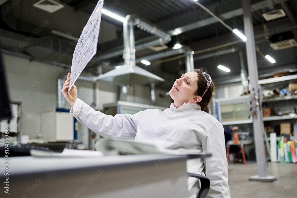 Serious lab technician sitting at table with carbon mesh Serious lab technician sitting at table with carbon mesh