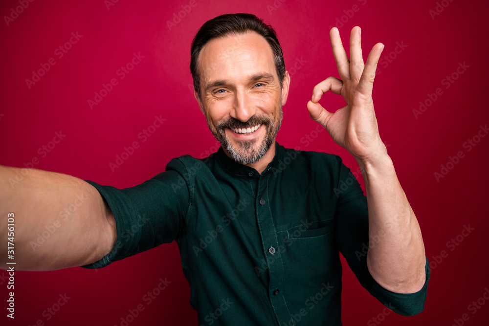 Self photo of cheerful toothy man showing ok sign taking selfie recording video demonstrating his face isolated vivid color background Self photo of cheerful toothy man showing ok sign taking selfie recording video demonstrating his face isolated vivid color background