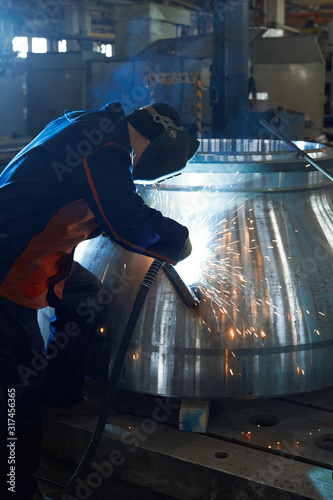 Fotografie A welder works with a large steel billet