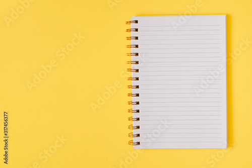 Open empty notebook on a yellow background. Top view.