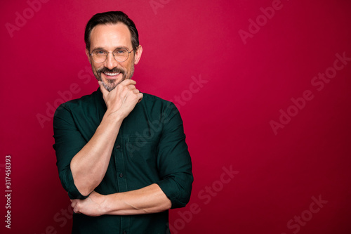 Photo of cheerful positive smart clever man standing near empty space touching his beard looking at you dreamily isolated vibrant color background