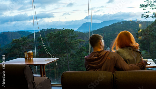 Young handsome man drinkink coffee and looking on beautiful mountains landscape on the amazing sunset.Tourist holding the cup of coffeewith beautiful mountains view. photo