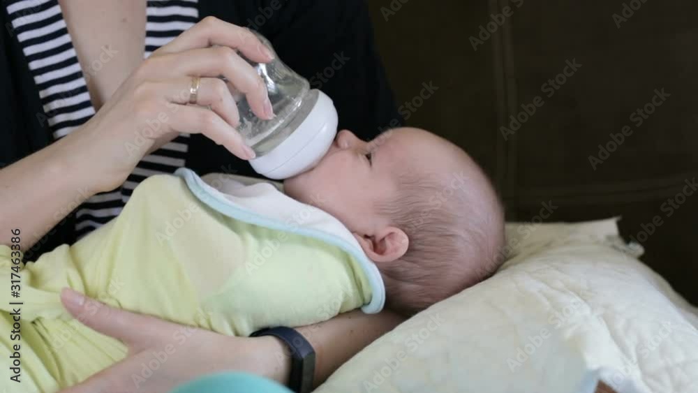 Little infant baby lying on mothers hand drinking milk from bottle. Baby food. Mom and child. Little infant baby lying on mothers hand drinking milk from bottle. Baby food. Mom and child.