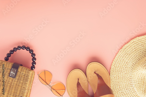 Summer fashion background on pink, trendy straw bag, fedora hat, leather sandals and yellow sunglasses, flat lay, top view, selective focus