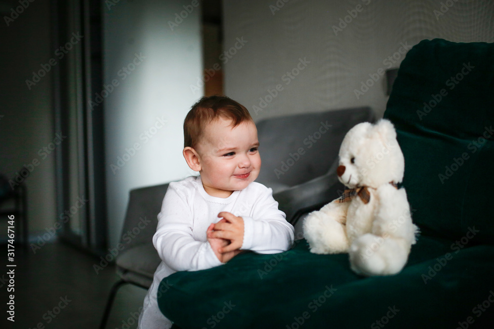 chubby Caucasian baby girl stands with soft toy chubby Caucasian baby girl stands with soft toy
