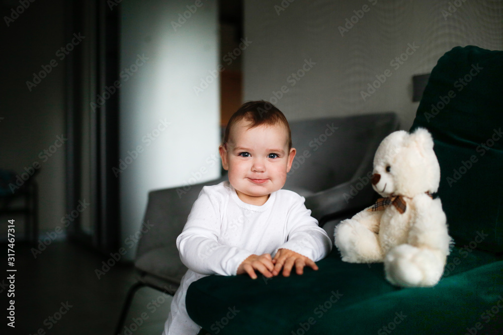 chubby Caucasian baby girl stands with soft toy chubby Caucasian baby girl stands with soft toy
