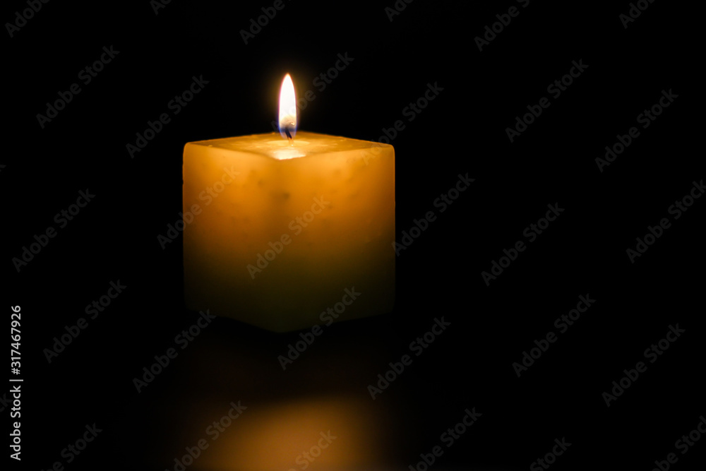 A lighted candle on a neutral black background, ideal for text application A lighted candle on a neutral black background, ideal for text application