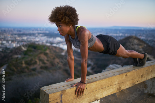 athletic african american woman working out doing pushups on bench at runyon canyon
